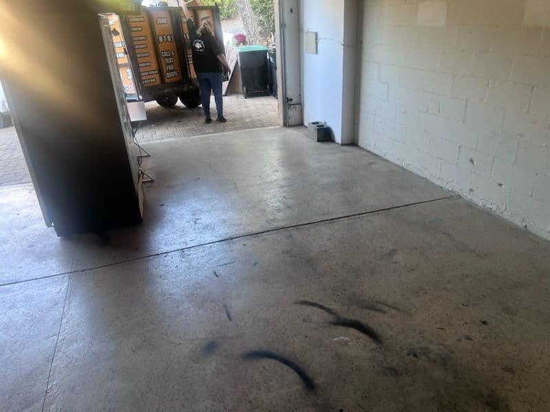 Empty garage space with a person holding papers and a food truck parked outside.